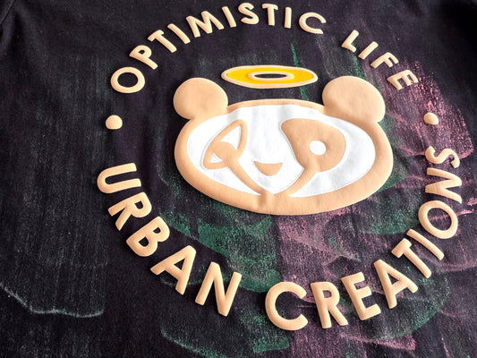 Black t-shirt with a bear logo and text 'Optimistic Life Urban Creations' on a dark background