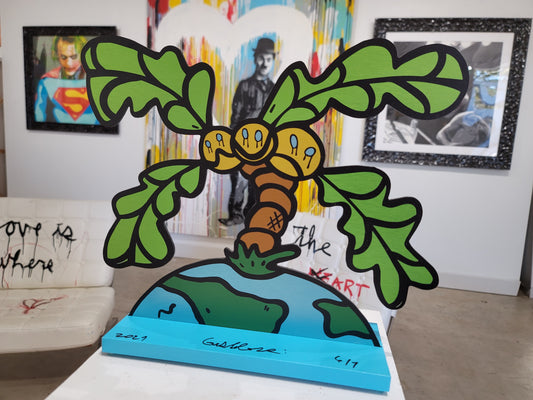 Colorful metal sculpture of a palm tree emerging from the earth.